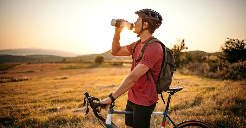 Ein Radfahrer trinkt Wasser aus einer Flasche bei einer Pause