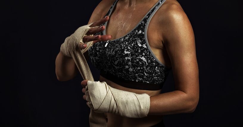 Eine Frau bindet sich Boxbandagen um die Hände