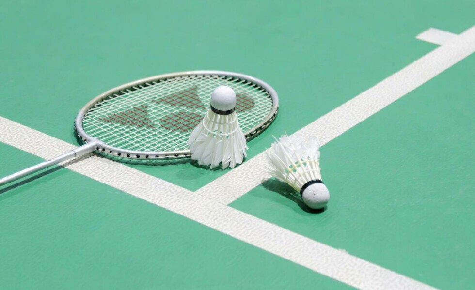 Badmintonschläger und Federbälle liegen auf einem Spielfeld