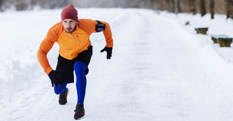Ein Mann joggt im Schnee und trägt eine Mütze