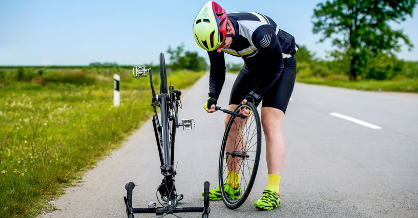 Ein Radfahrer repariert sein Fahrrad auf einer Landstraße