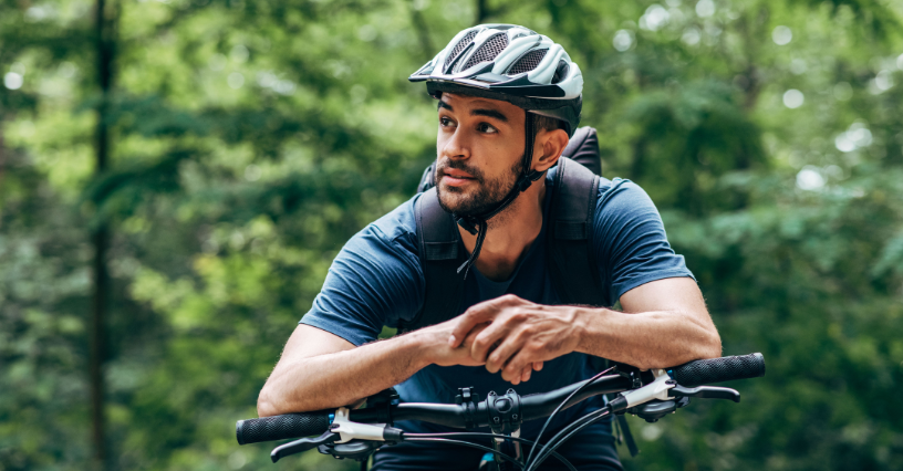 Ein Mann auf einem Fahrrad blickt in den Wald