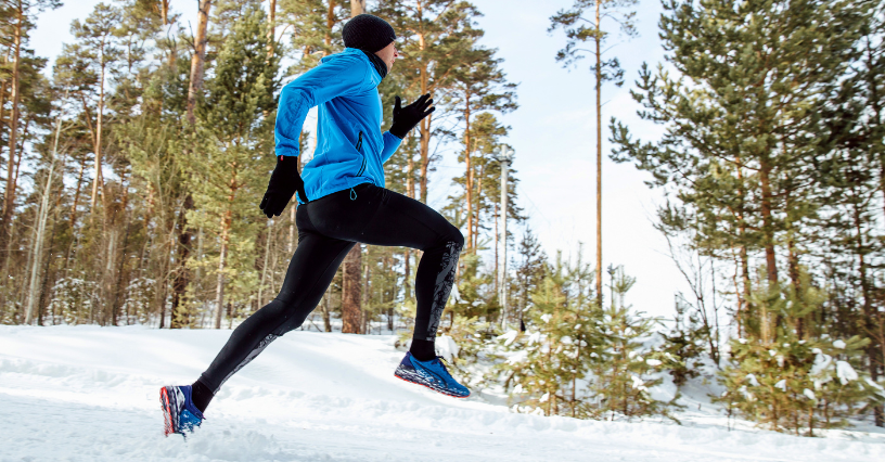 Ein Läufer joggt im Schnee durch einen Wald