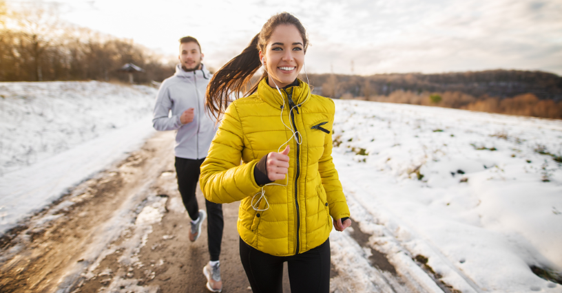 Zwei Personen joggen auf einem schneebedeckten Weg
