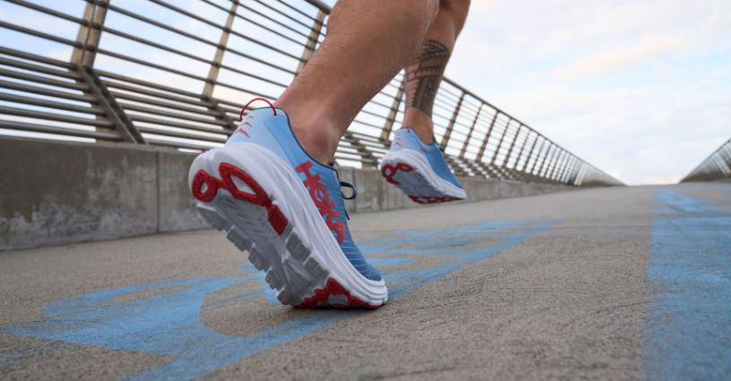 Eine Person joggt auf einer Brücke und trägt dabei bequeme Laufschuhe von Hoka