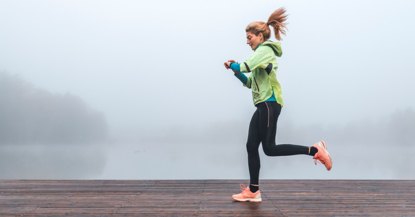 Eine Person joggt entlang eines hölzernen Stegs in nebliger Umgebung