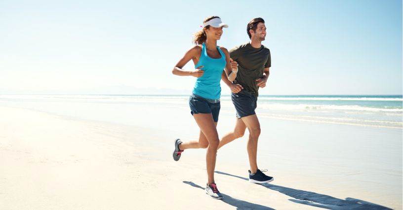 Zwei Menschen joggen am Strand entlang
