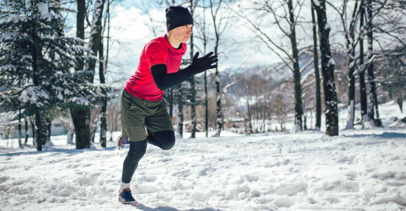 Mann joggt im Schnee und trägt Sportbekleidung