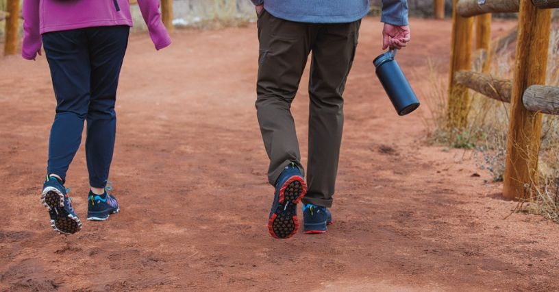 Zwei Personen gehen auf einem Weg mit Sportbekleidung und tragen eine Flasche
