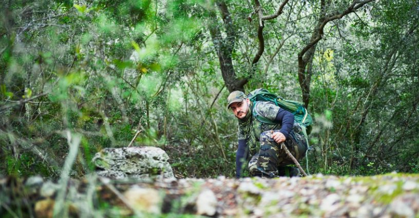 Ein Wanderer bewegt sich durch dichtes Waldgebiet mit einem Rucksack