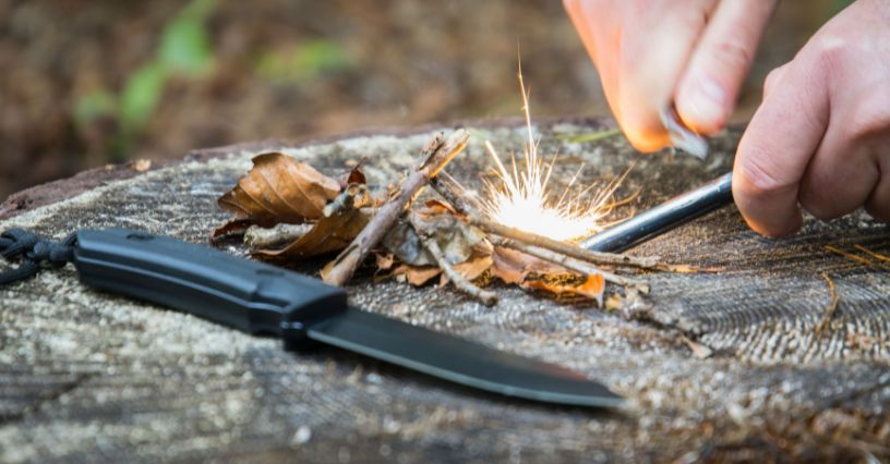 Ein Messer und Funken bei der Feuererzeugung auf einem Baumstumpf