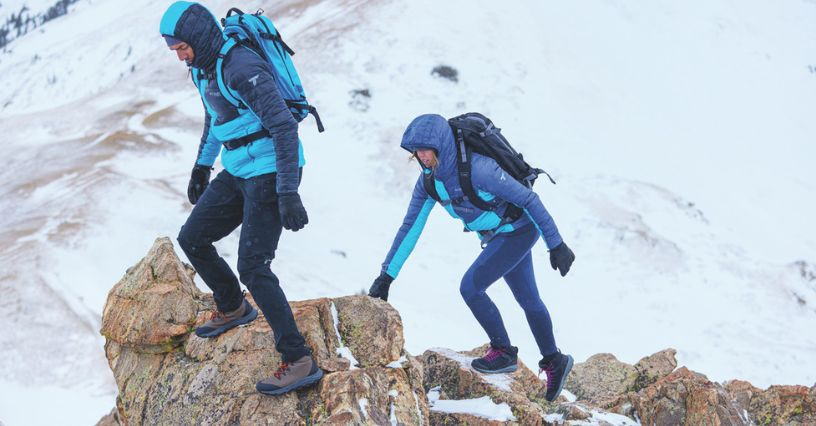 Zwei Personen klettern im Schnee auf einen Berg