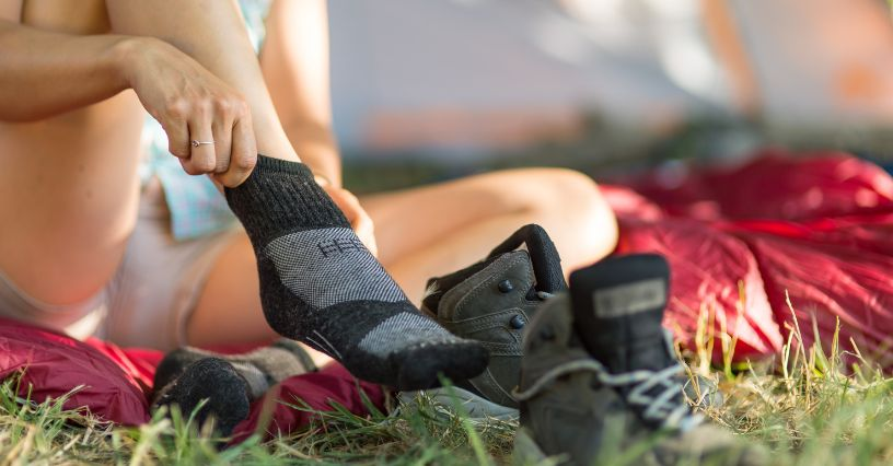 Eine Person zieht im Freien Wandersocken an