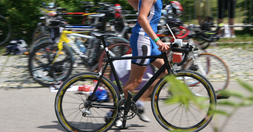 Ein Sportler schiebt sein Fahrrad bei einem Triathlon