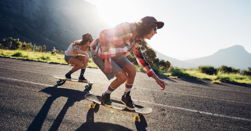 Zwei Personen fahren auf Longboards eine Straße entlang