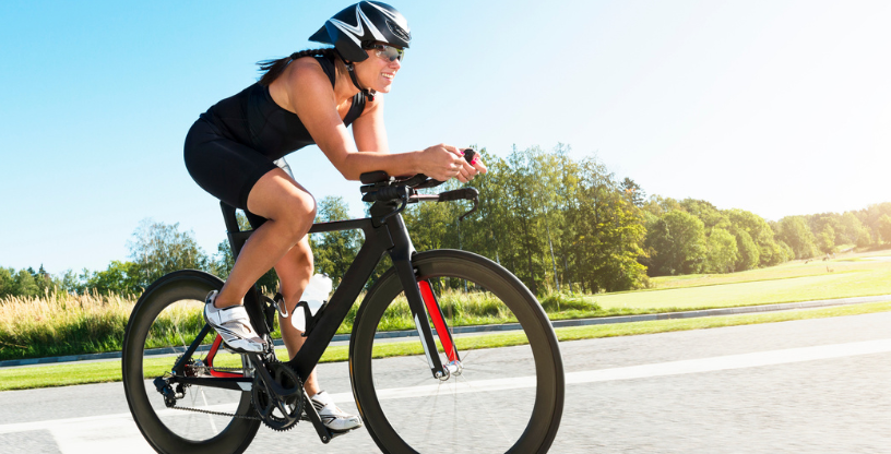 Eine Person fährt auf einem Fahrrad auf einer Straße in der Sonne
