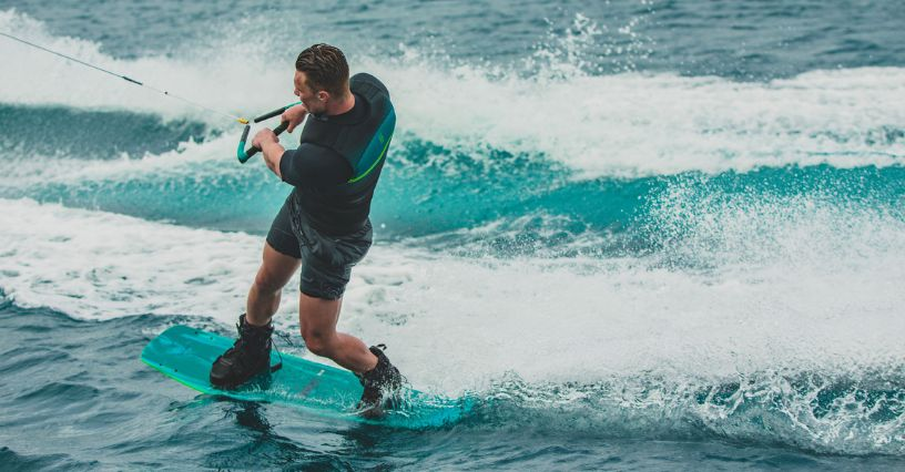 Ein Mensch fährt Wakeboard auf dem Wasser