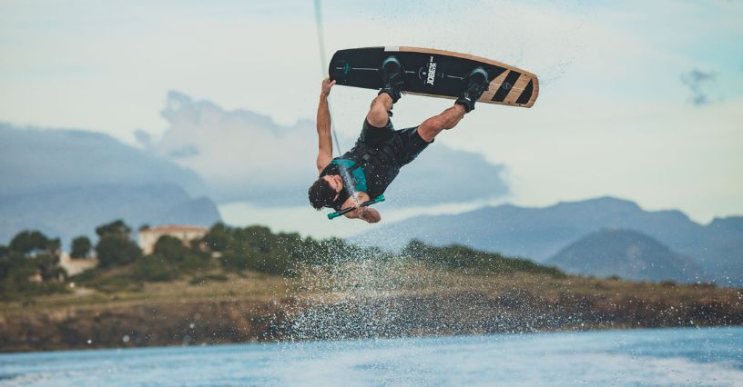 Ein Sportler springt mit einem Wakeboard über Wasser