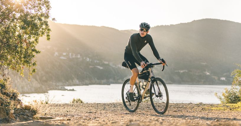 Ein Radfahrer fährt auf einem steinigen Weg entlang eines Sees