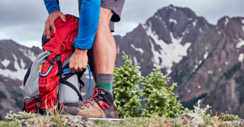 Eine Person packt einen Rucksack vor einer Bergkulisse