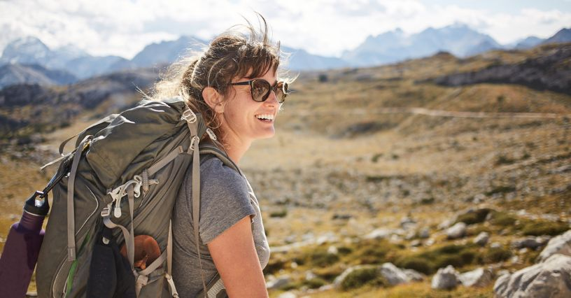 Eine Frau mit Rucksack genießt eine Wanderung in den Bergen