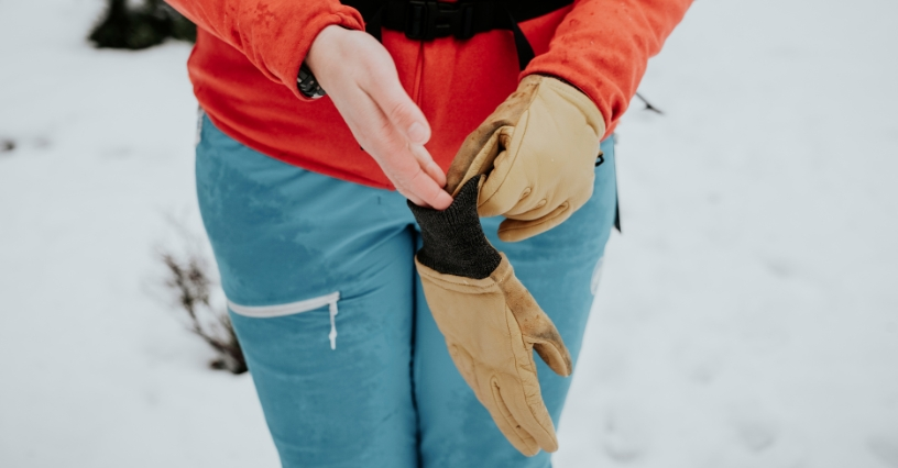 Eine Person zieht Lederhandschuhe über ihre warme Kleidung an