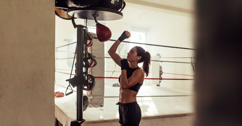 Eine Frau trainiert mit einem Boxsack im Fitnessstudio