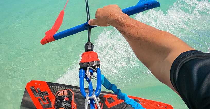 Eine Person steuert ein Kitesurfbrett auf dem Wasser