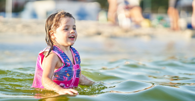 Ein Kind trägt eine Schwimmweste im Wasser