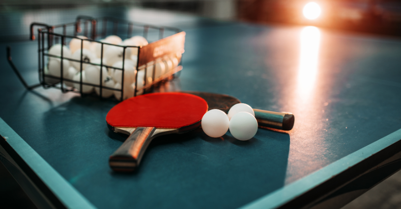 Ein Tischtennisschläger und Bälle liegen auf einem Tisch