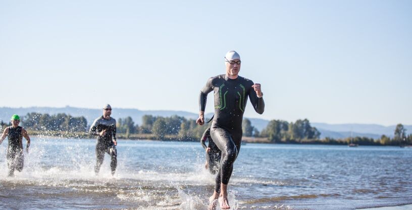 Triathleten laufen aus dem Wasser während eines Wettkampfs
