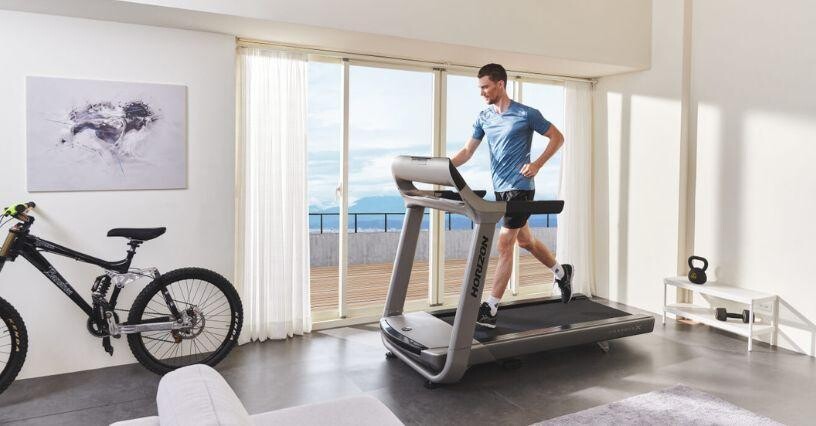 Ein Mann läuft auf einem Laufband in einem hellen Zimmer