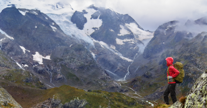 Eine Person steht in den Bergen mit einem großen Rucksack