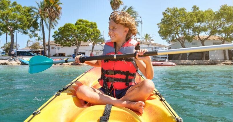 Ein Kind paddelt in einem Kajak auf dem Wasser