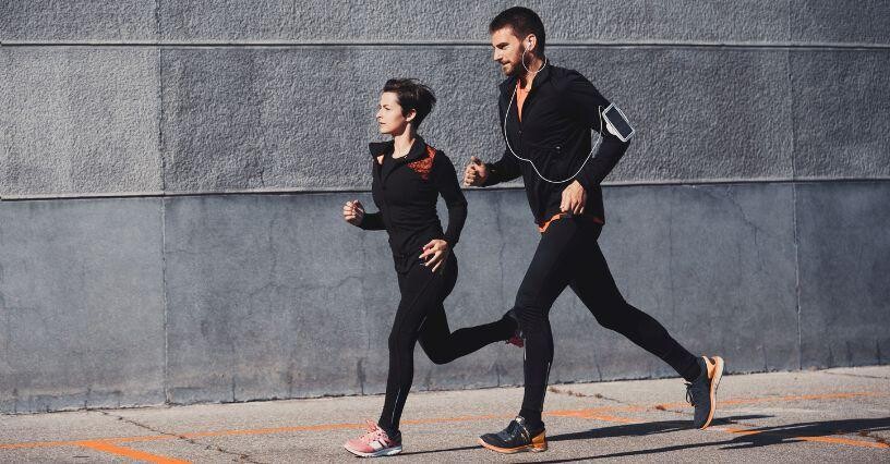 Zwei Personen joggen nebeneinander in Sportkleidung